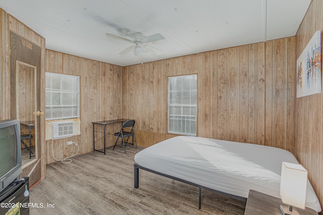 bedroom featuring ceiling fan, light hardwood / wood-style flooring, and wood walls