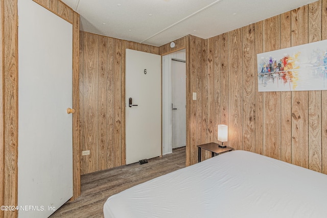 bedroom with dark hardwood / wood-style flooring and wood walls