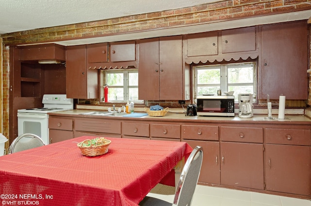 kitchen with sink, electric stove, tile floors, and a textured ceiling