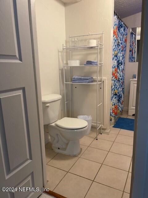 bathroom featuring tile flooring and toilet