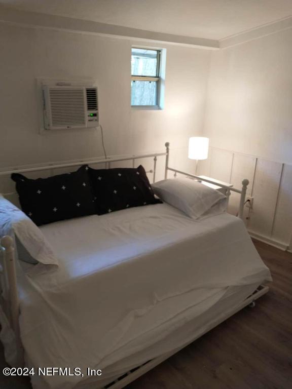 bedroom with dark hardwood / wood-style floors, crown molding, and a wall mounted air conditioner