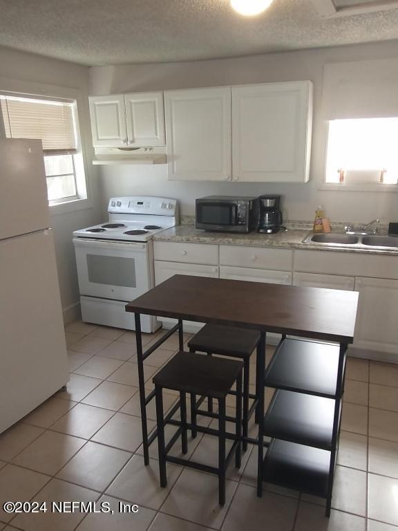 kitchen featuring a textured ceiling, white appliances, white cabinets, sink, and light tile floors