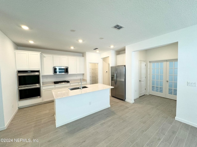 kitchen with white cabinetry, appliances with stainless steel finishes, sink, and an island with sink