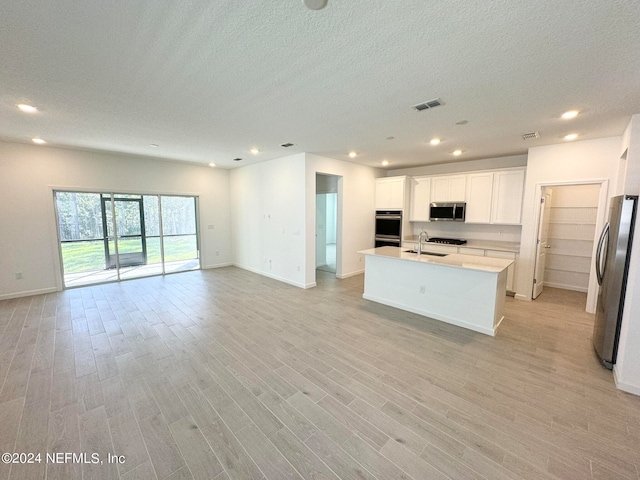 kitchen featuring an island with sink, white cabinetry, sink, stainless steel appliances, and light hardwood / wood-style flooring