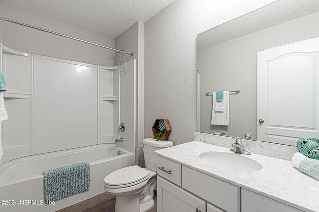 full bathroom with a textured ceiling, oversized vanity, toilet, and shower / washtub combination