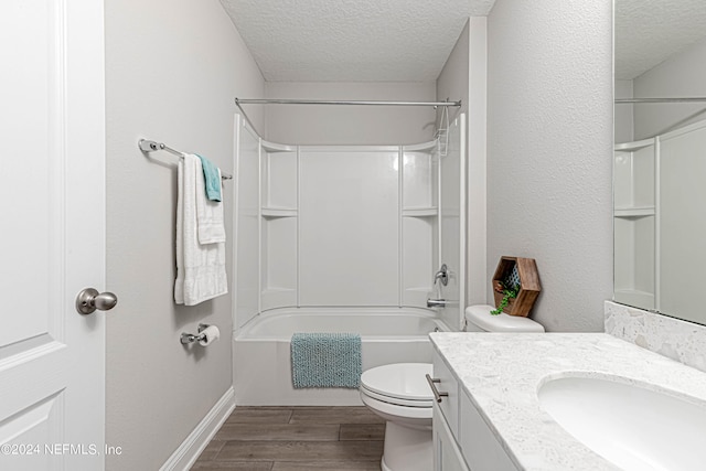 full bathroom with vanity with extensive cabinet space, tub / shower combination, a textured ceiling, toilet, and hardwood / wood-style flooring