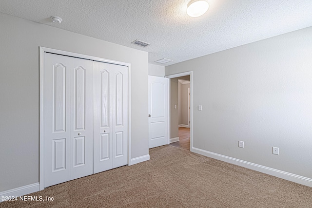 unfurnished bedroom with a closet, carpet flooring, and a textured ceiling