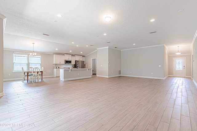 unfurnished living room with ornamental molding, light hardwood / wood-style flooring, a wealth of natural light, and a textured ceiling