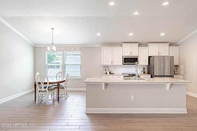 kitchen with stainless steel appliances, decorative light fixtures, an island with sink, and a kitchen bar