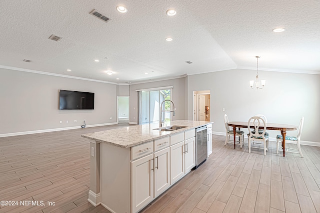 kitchen with pendant lighting, ornamental molding, a center island with sink, vaulted ceiling, and sink