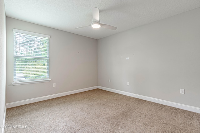 spare room featuring plenty of natural light, carpet floors, and ceiling fan