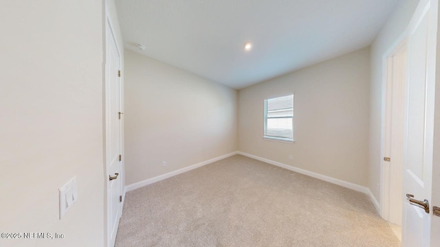 unfurnished room with baseboards, vaulted ceiling, and light colored carpet