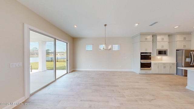 kitchen featuring stainless steel appliances, light wood-style floors, light countertops, and a notable chandelier