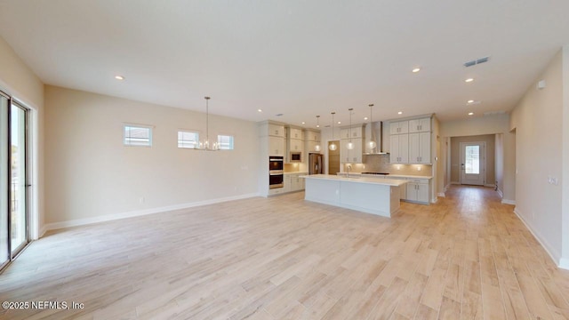 kitchen with open floor plan, light countertops, visible vents, and light wood finished floors