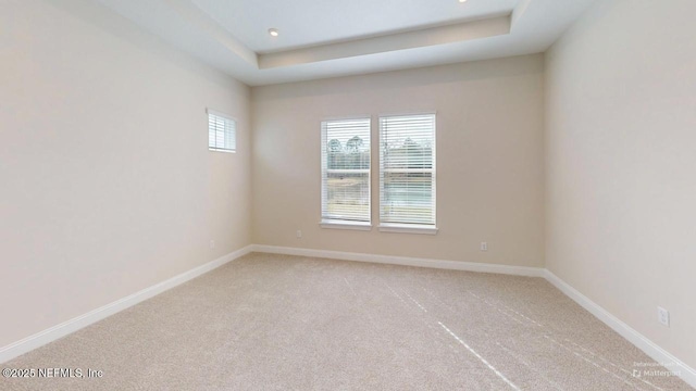 empty room with light carpet, baseboards, a tray ceiling, and recessed lighting