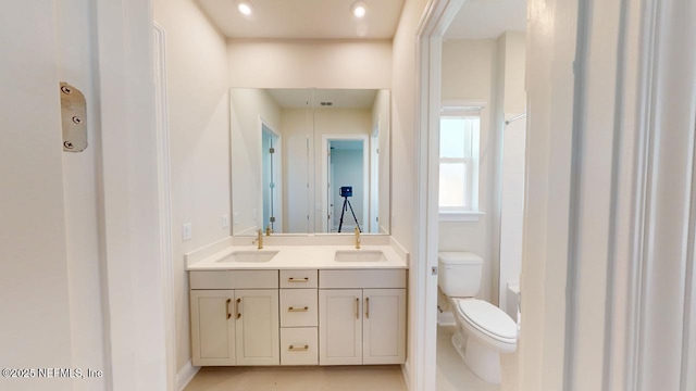 bathroom featuring toilet, double vanity, walk in shower, and a sink