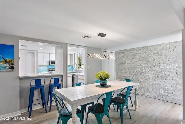 dining room featuring sink, light hardwood / wood-style floors, and a chandelier