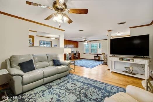 living room with wood-type flooring, ceiling fan, and crown molding