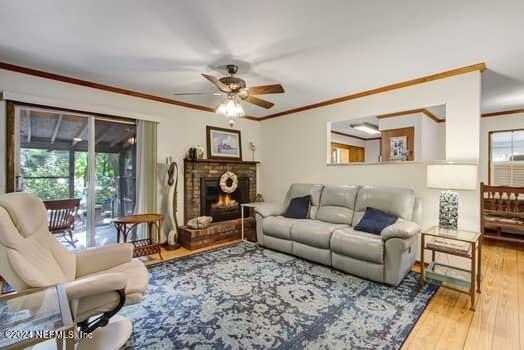 living room featuring ornamental molding, ceiling fan, hardwood / wood-style flooring, and a fireplace