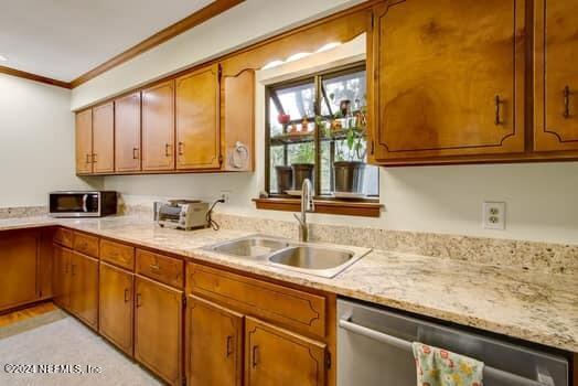 kitchen with sink, appliances with stainless steel finishes, crown molding, and light stone countertops