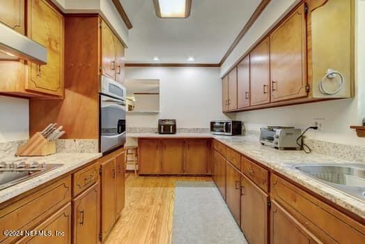 kitchen with fume extractor, stainless steel oven, light wood-type flooring, and ornamental molding