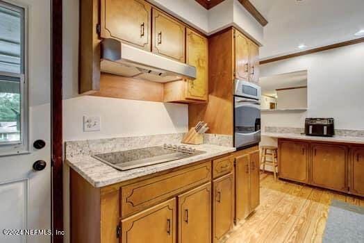 kitchen with crown molding, light hardwood / wood-style flooring, stainless steel oven, and black electric stovetop