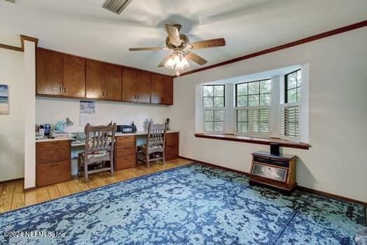 home office with crown molding, ceiling fan, and light wood-type flooring