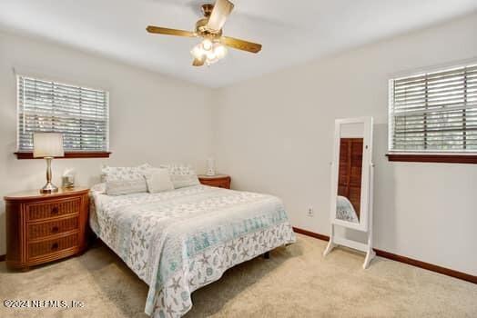 carpeted bedroom featuring multiple windows and ceiling fan