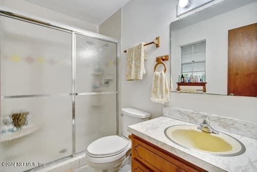 bathroom with walk in shower, vanity, and toilet