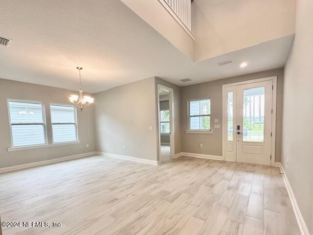 foyer entrance with baseboards, light wood-style floors, a healthy amount of sunlight, and an inviting chandelier