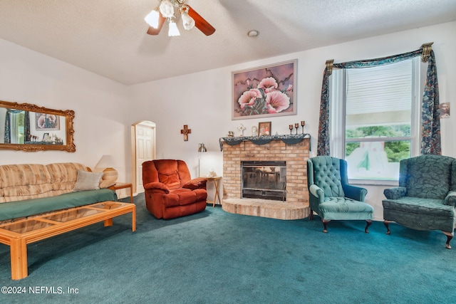 living room featuring carpet, ceiling fan, a textured ceiling, and a fireplace