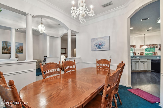 carpeted dining room with ornamental molding, ornate columns, a textured ceiling, and a chandelier