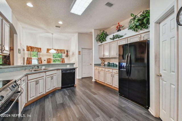 kitchen with dark wood-type flooring, hanging light fixtures, black appliances, and a textured ceiling