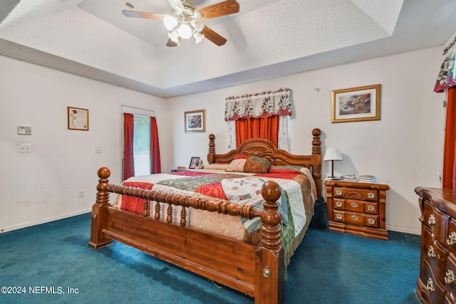 carpeted bedroom featuring ceiling fan, a raised ceiling, and a textured ceiling