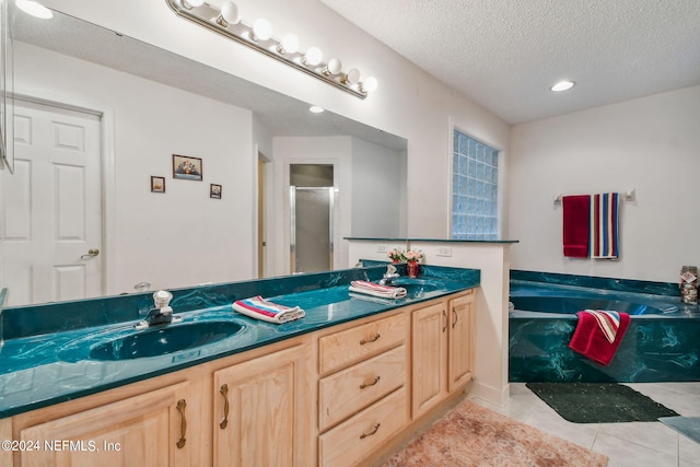 bathroom featuring a textured ceiling, tile floors, double vanity, and a bath