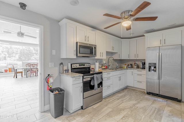 kitchen with ceiling fan, white cabinets, light tile floors, and appliances with stainless steel finishes