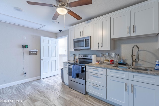 kitchen featuring white cabinetry, stainless steel appliances, sink, light tile flooring, and ceiling fan