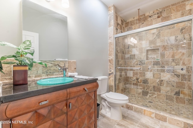 bathroom with vanity with extensive cabinet space, an enclosed shower, toilet, and tile floors