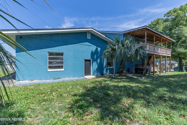 rear view of house with a wooden deck and a lawn