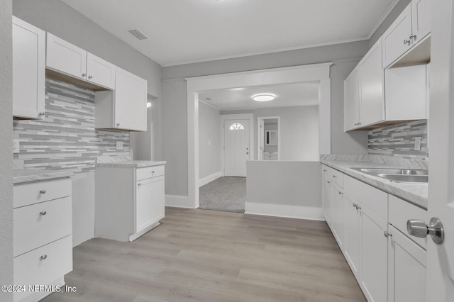 kitchen with backsplash, sink, light wood-type flooring, and white cabinets