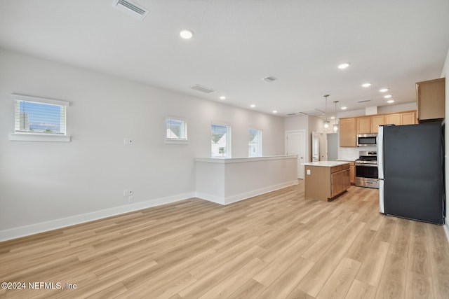 kitchen featuring a healthy amount of sunlight, hanging light fixtures, a kitchen island, and stainless steel appliances