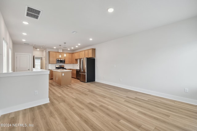 kitchen featuring a kitchen island, light wood-type flooring, stainless steel appliances, and hanging light fixtures