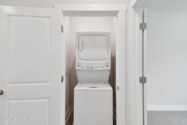 laundry room featuring carpet floors and stacked washer / dryer