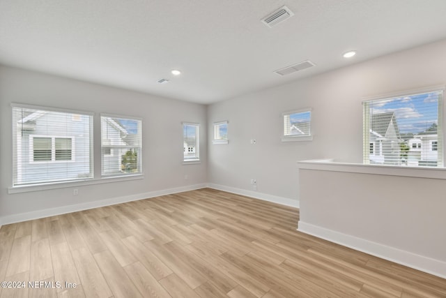 spare room featuring light hardwood / wood-style flooring and plenty of natural light