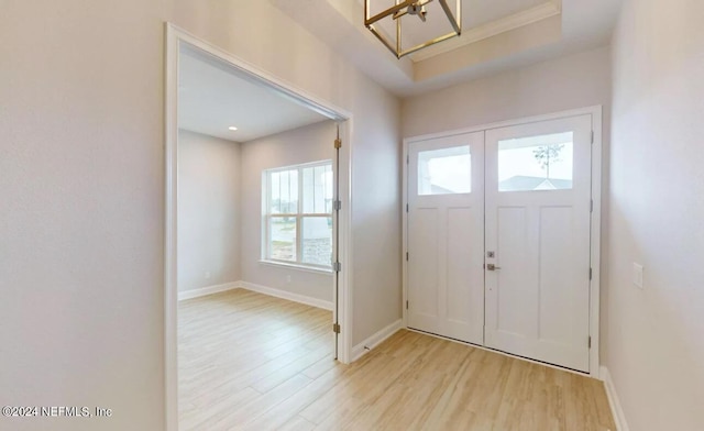 foyer entrance with light wood-type flooring, an inviting chandelier, and plenty of natural light