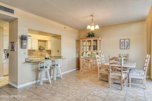 dining space with a textured ceiling, a notable chandelier, and light tile floors