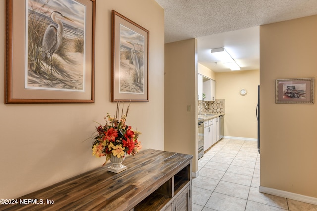 hallway featuring a textured ceiling, sink, and light tile floors