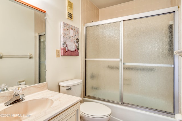 full bathroom featuring toilet, shower / bath combination with glass door, and vanity