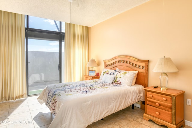 tiled bedroom featuring ceiling fan, access to exterior, expansive windows, and a textured ceiling