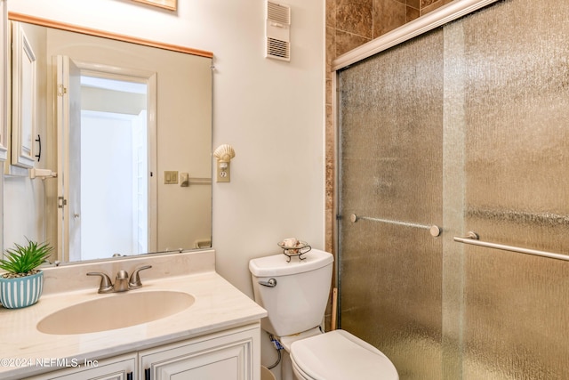 bathroom featuring a shower with door, toilet, and large vanity